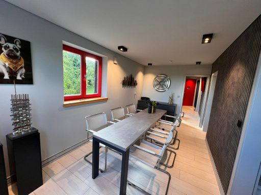 Moderner Besprechungsraum mit Tisch, Stühlen und einem Hundeporträt an der Wand.