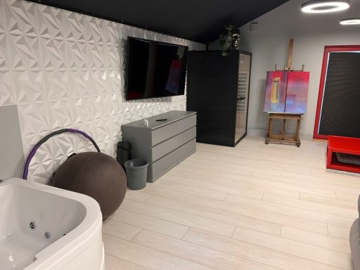 Moderne Inneneinrichtung mit Badewanne, TV, Kommode und farbigem Gemälde.